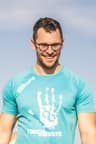 Mann im blauen Shirt geht durch den Sand