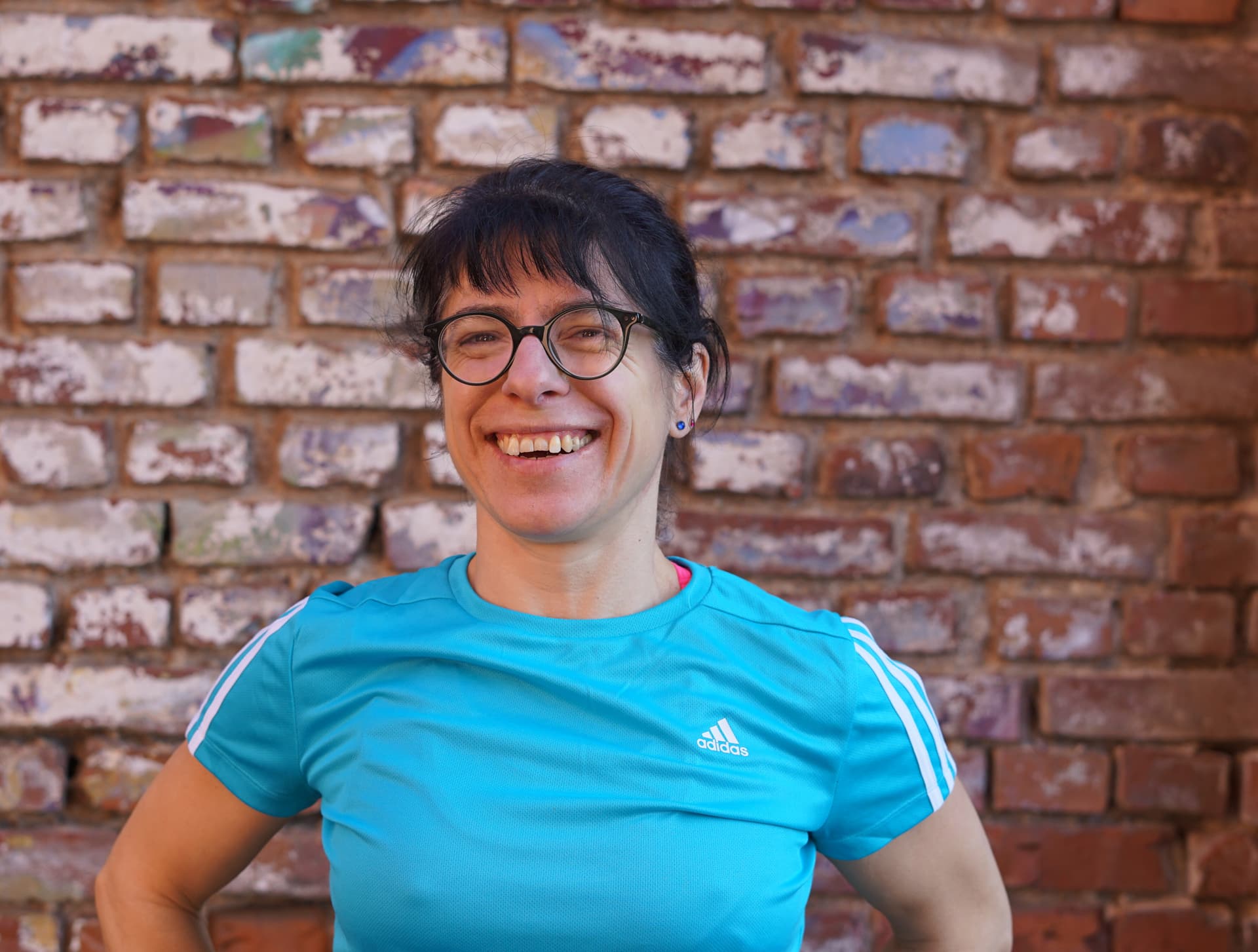 Fitness Trainerin Iris Berger steht vor Wand und lacht
