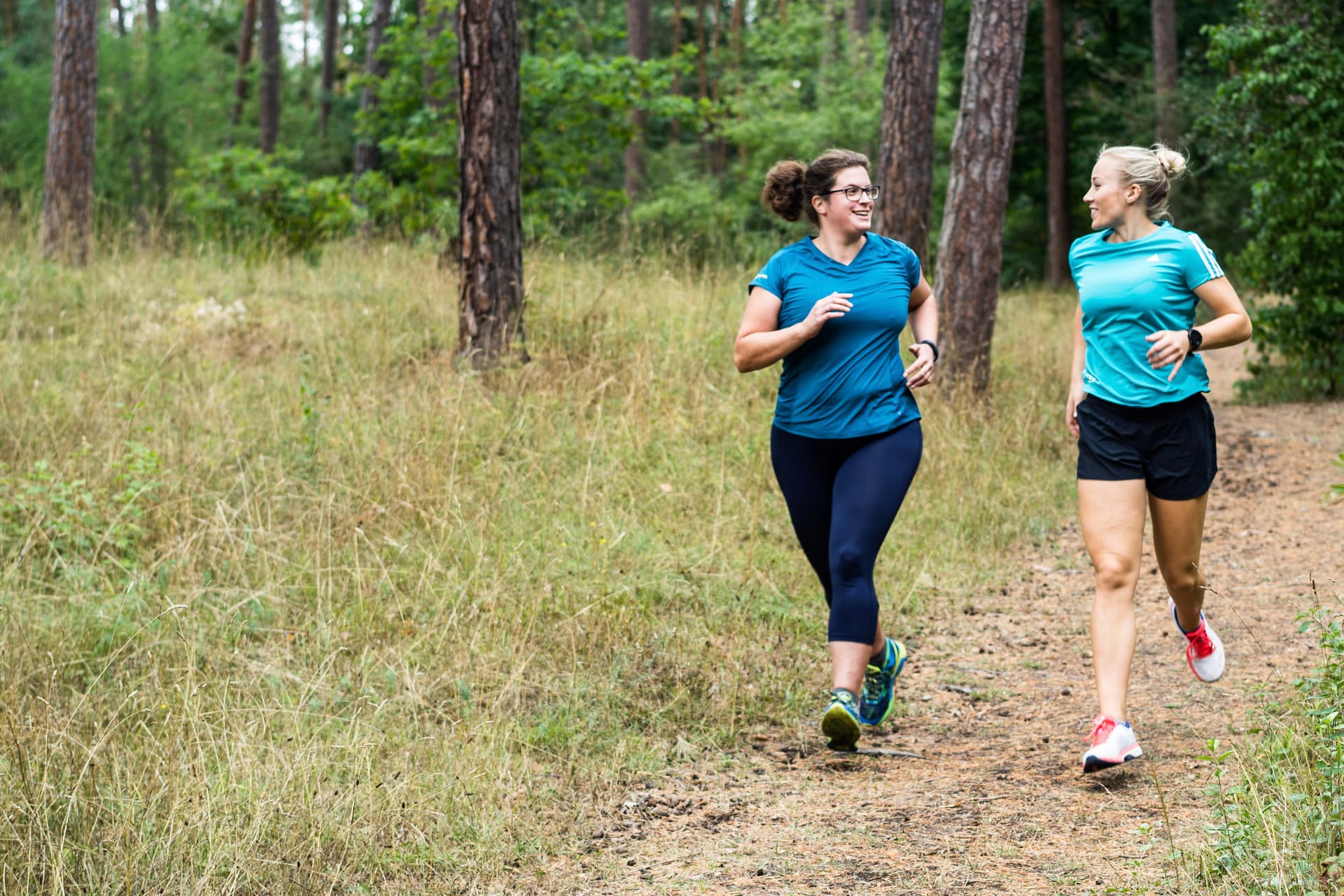 Ein Bootie und eine Trainerin laufen gemeinsam durch den Wald