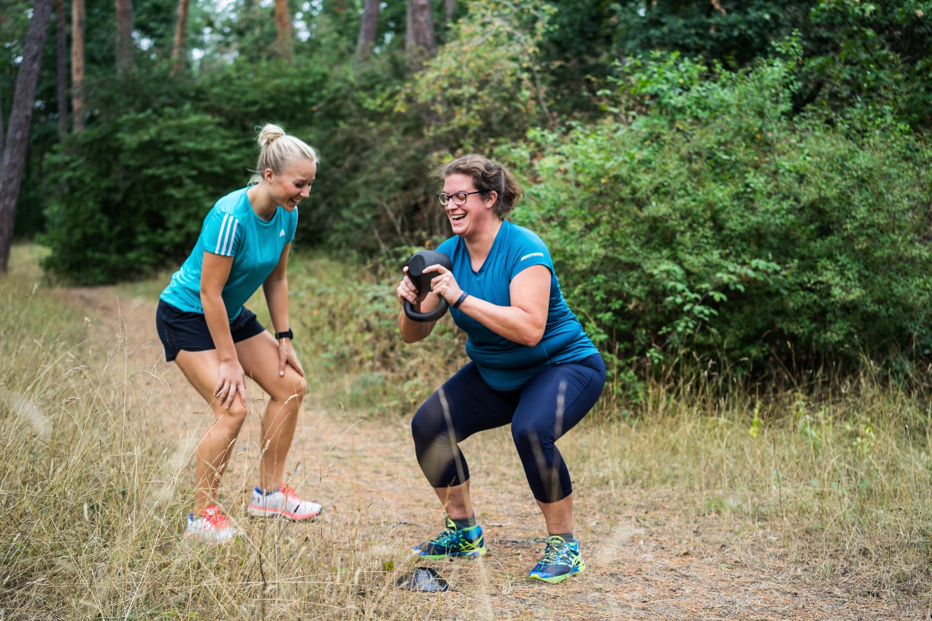 Trainerin korrigiert ein Bootie beim Training mit Kettlebells
