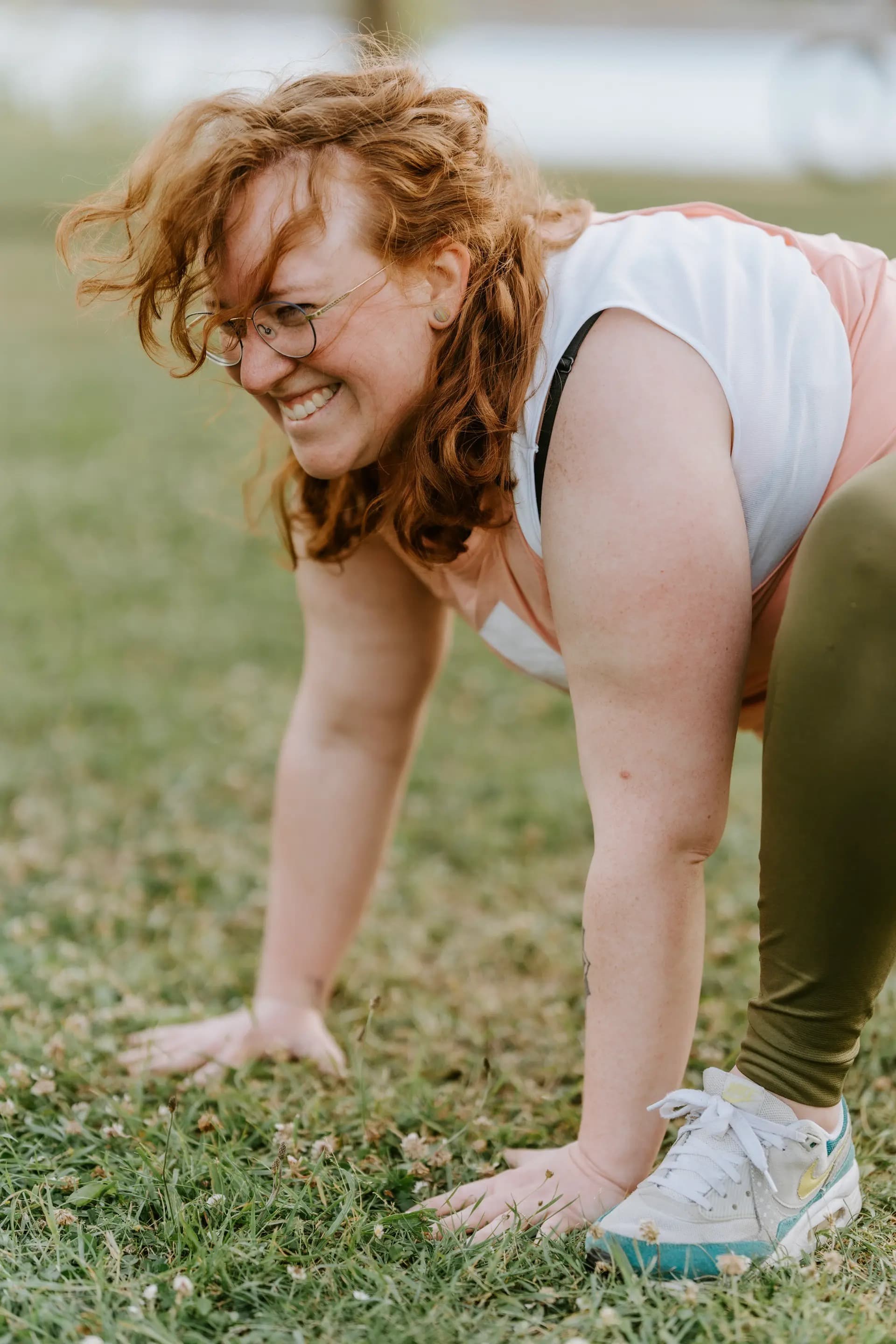 Frau beim Outdoor Bootcamp in Wiesbaden, Helmut Schön Sportpark, lachend während einer Bodenübung. Outdoor Fitness und Training in der Natur.