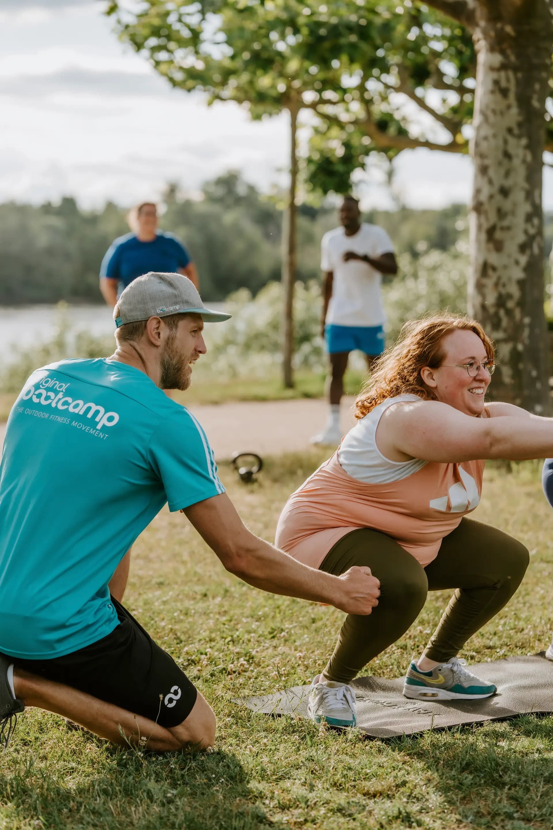 Trainer gibt individuelle Anweisungen bei einer Kniebeugen-Übung während eines Outdoor Trainings in Köln, Friedenspark. Personal Coaching für maximale Erfolge.
