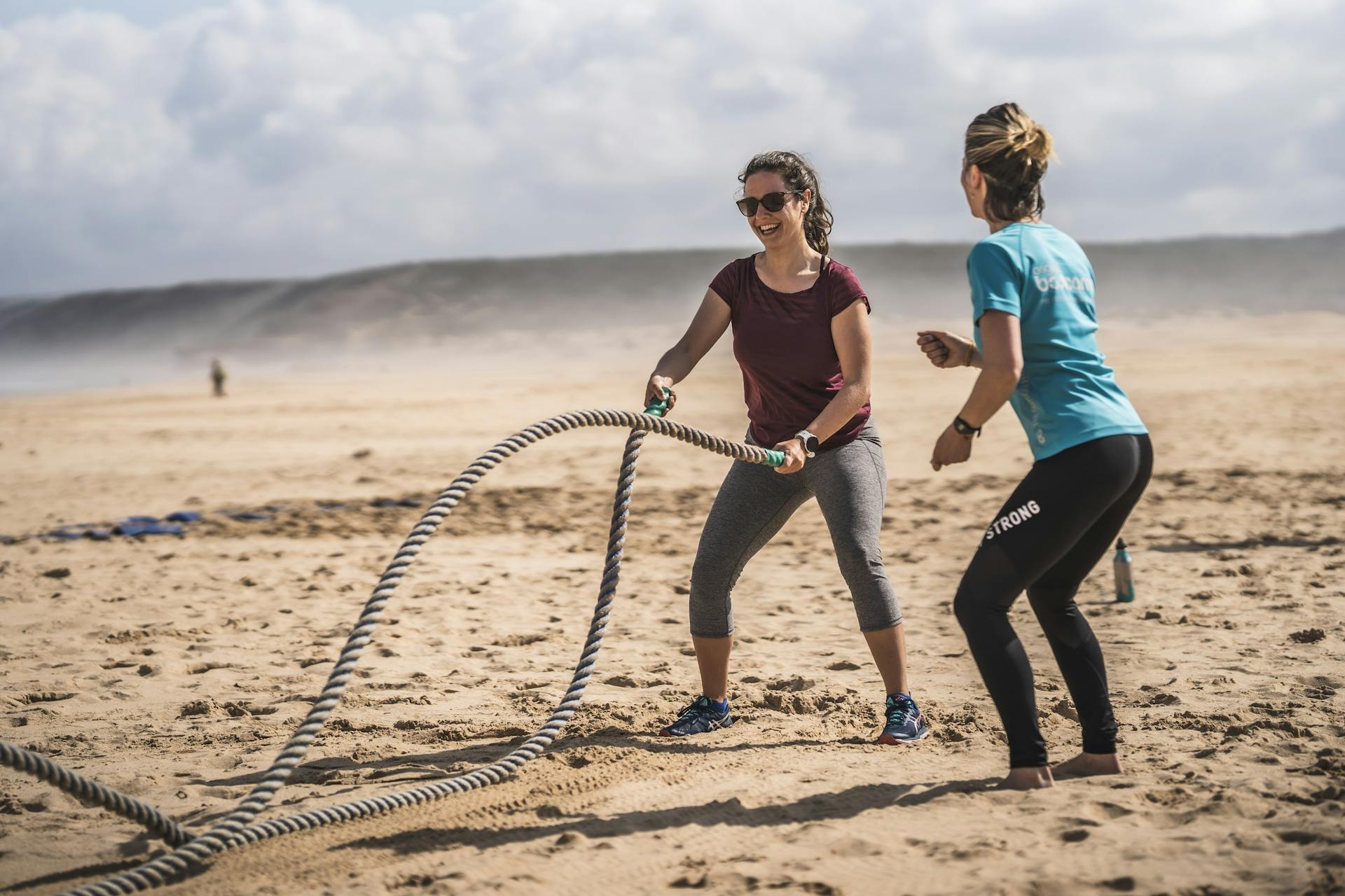 Die Trainerin eines Fitness Retreats erklärt die Sportübung am Strand