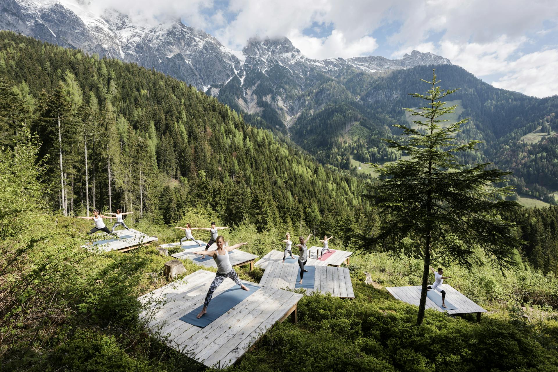 Eine Gruppe von Fitnessreisenden trainiert mit Blick auf die österreichischen Berge