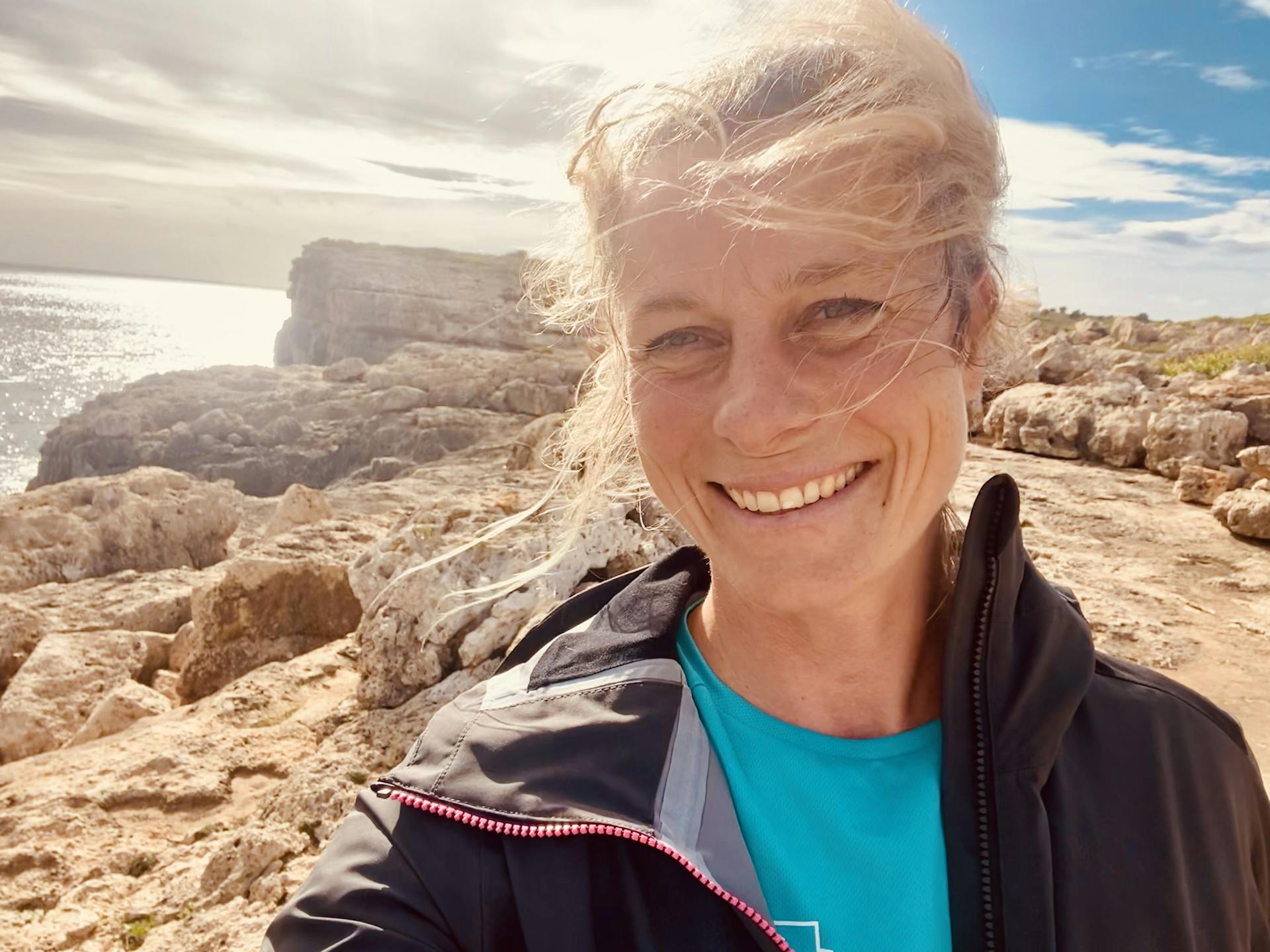Lächelnde Personal Trainerin Saskia Barkhoff vor dem Meer in Mallorca