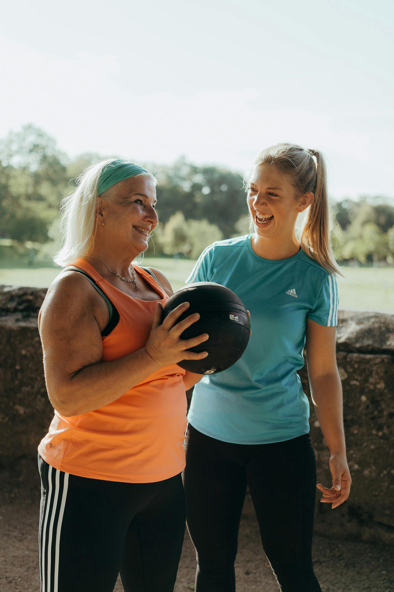 Eine Trainerin unterstützt eine 60 jährige Teilnehmerin bei der Übung mit dem Slamball