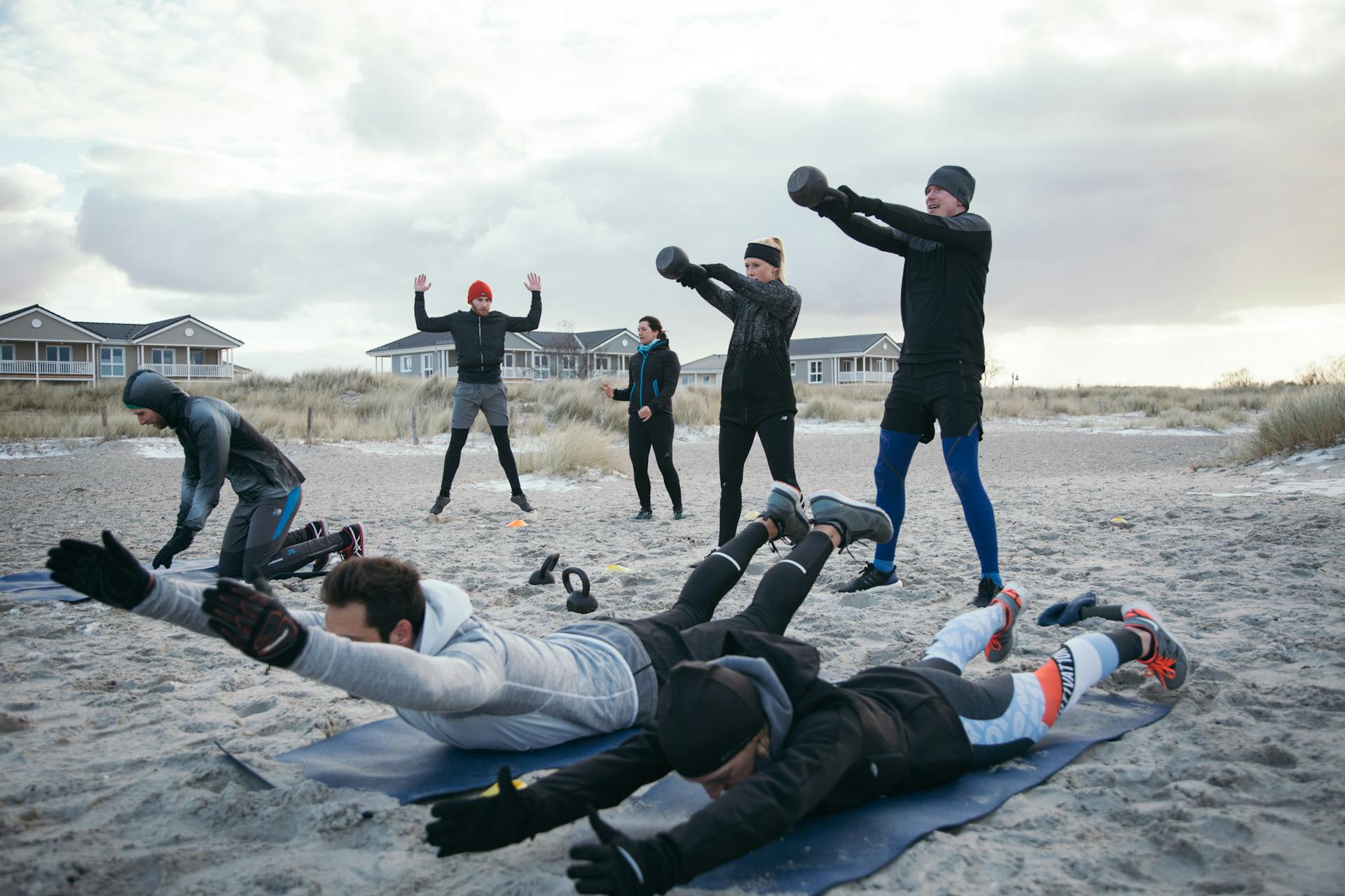 Menschen beim Workout mit Kettlebell und Matte am Strand der Ostsee