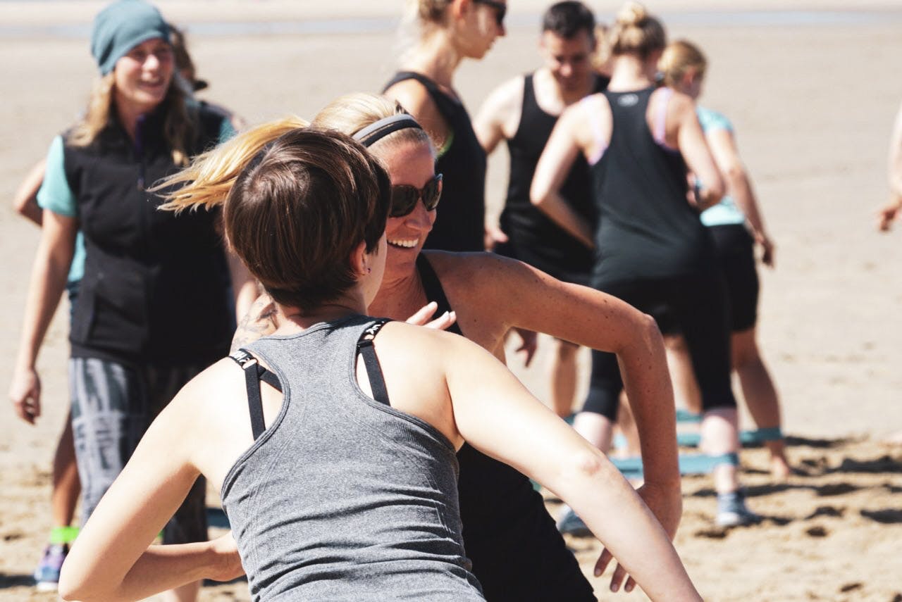 Strahlende Bootcamp Teilnehmerinnen beim Workout am Strand in Holland