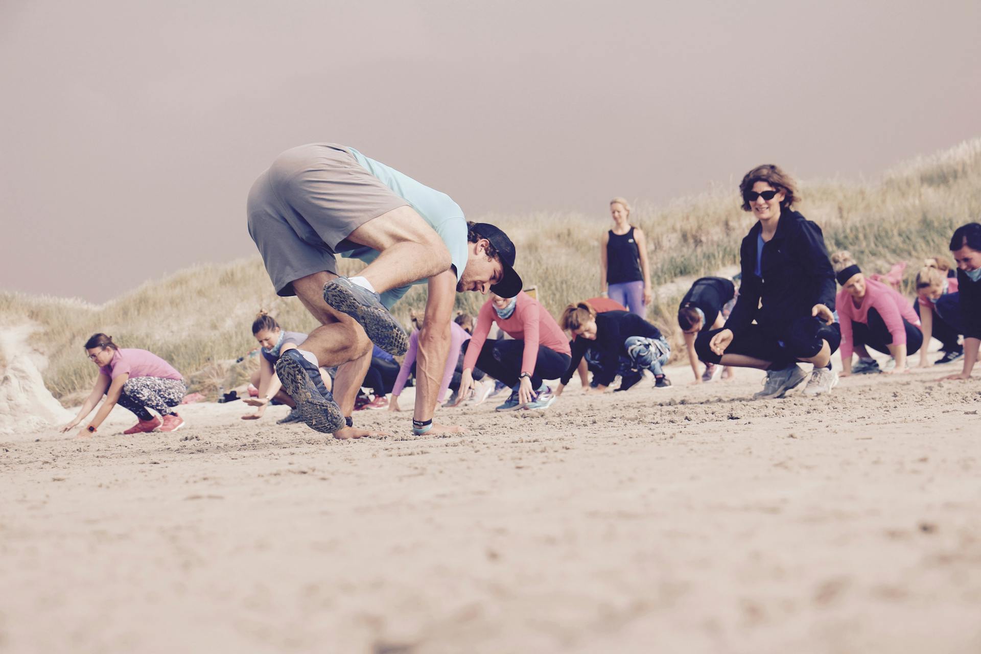 Trainer beim Vormachen einer Fitness Übung am Strand