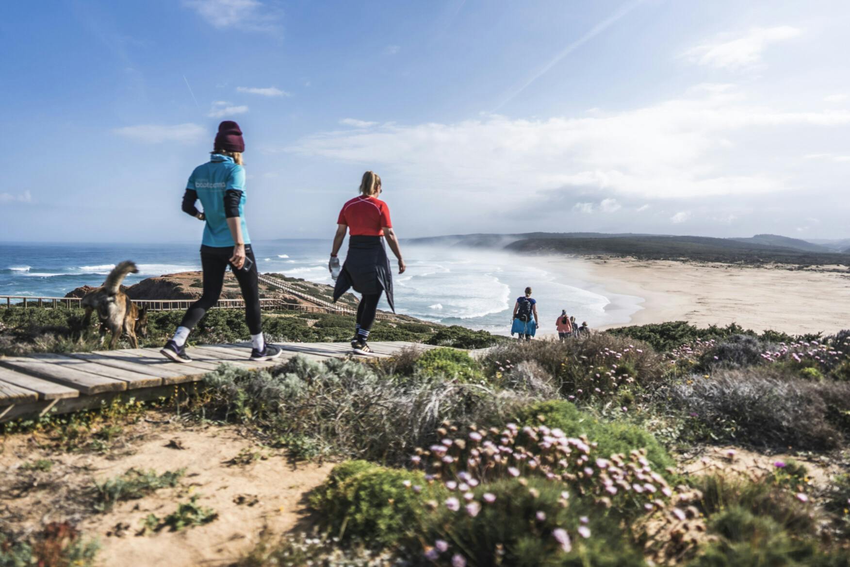 Teilnehmerinnen laufen eine Düne am Strand in Portugal herunter
