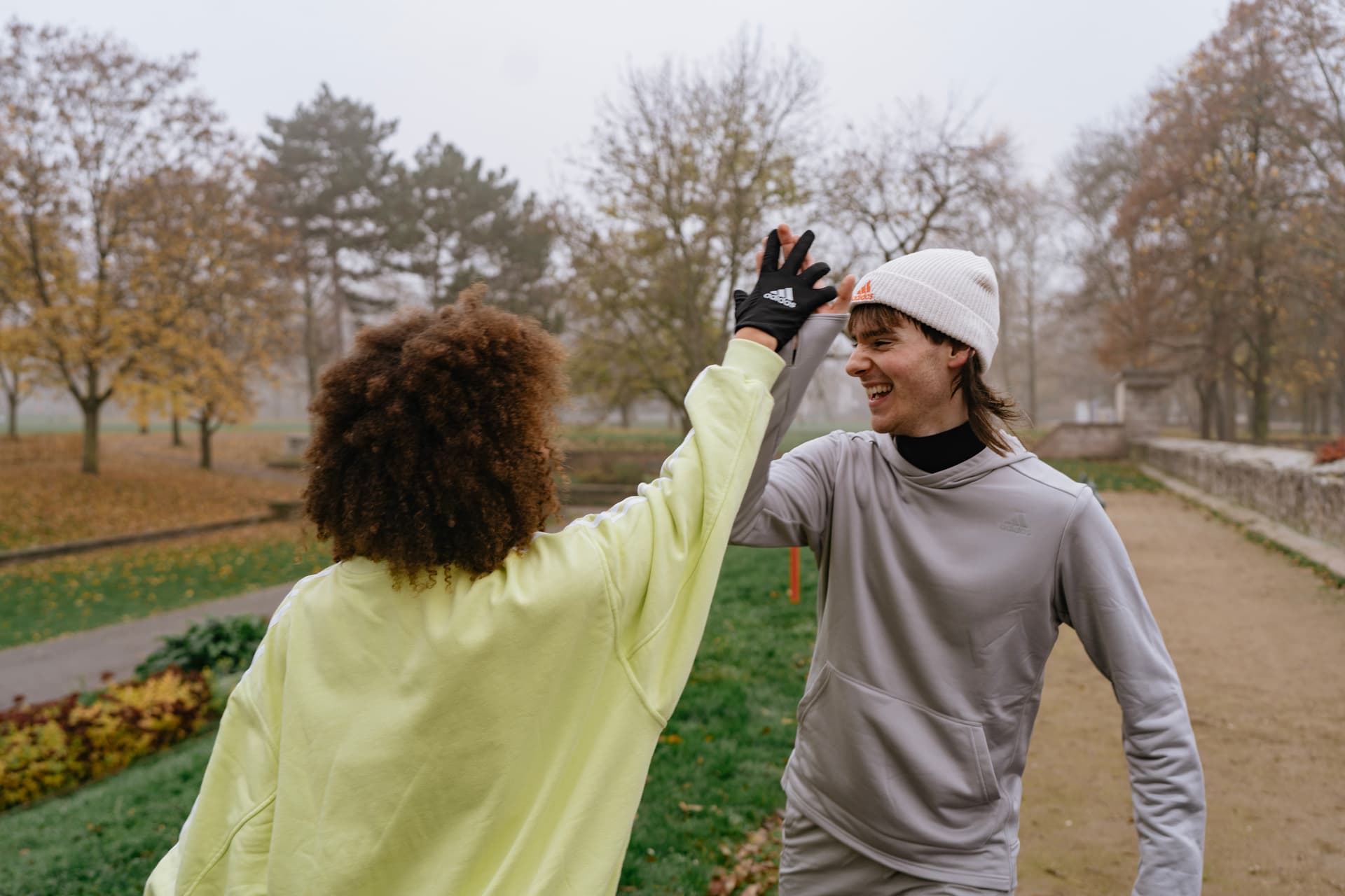 Zwei Sportler/innen im Park klatschen sich nach einem erfolgreichen Training ein