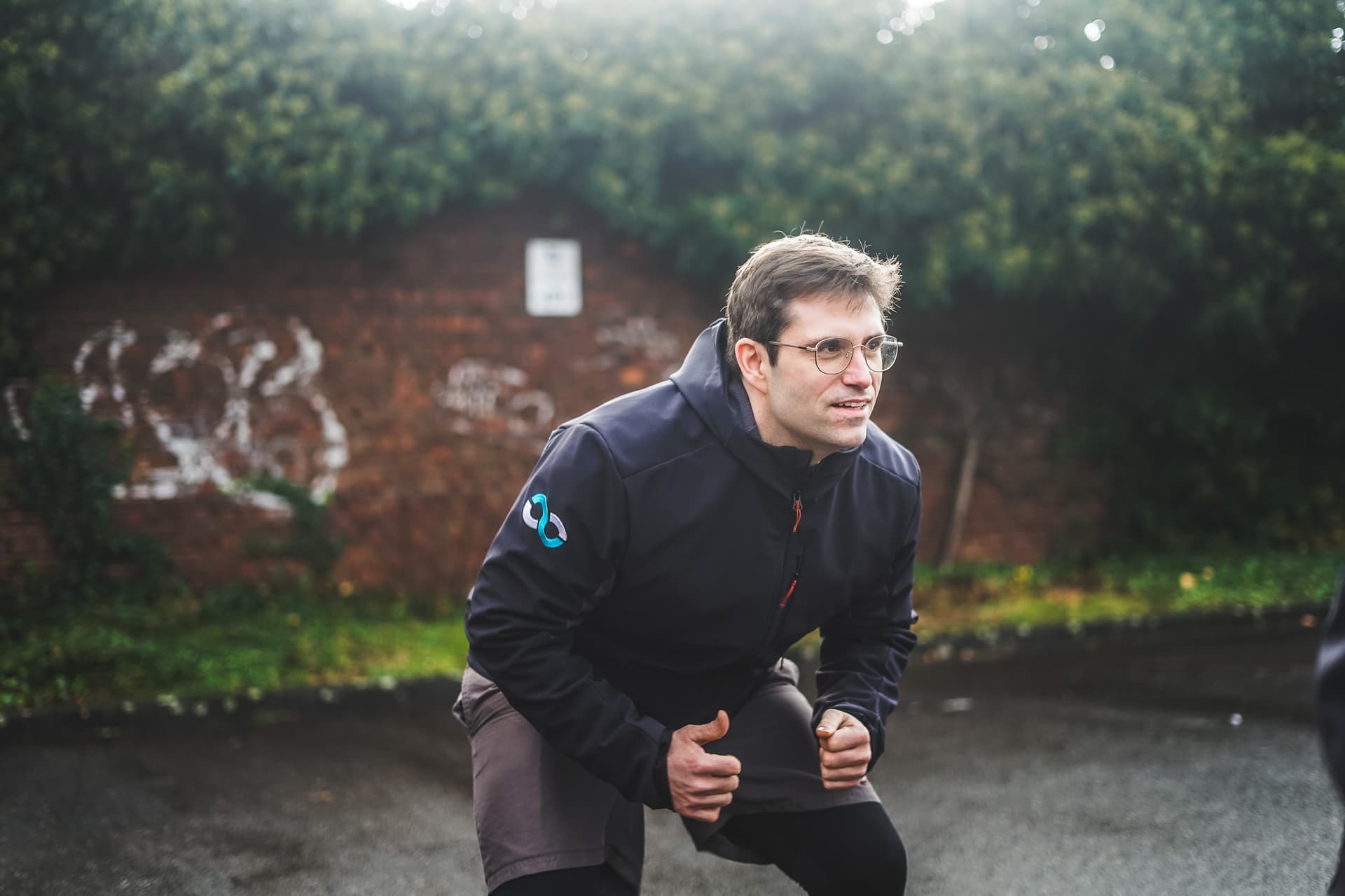 Personal Trainer Markus Jahnke in einer Kniebeuge vor einer begrünten Backsteinwand