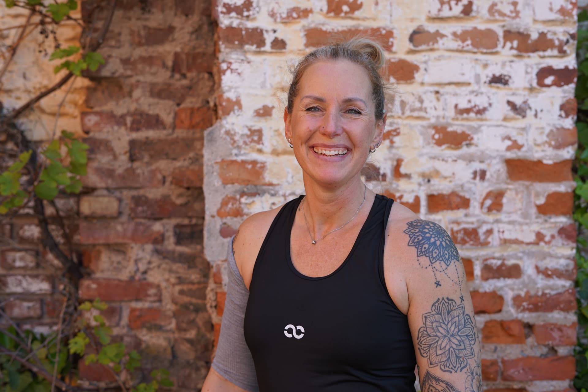 Nadine Personal Coach aus Düsseldorf lächelt in die Kamera und trägt ein blaues langarm Oberteil