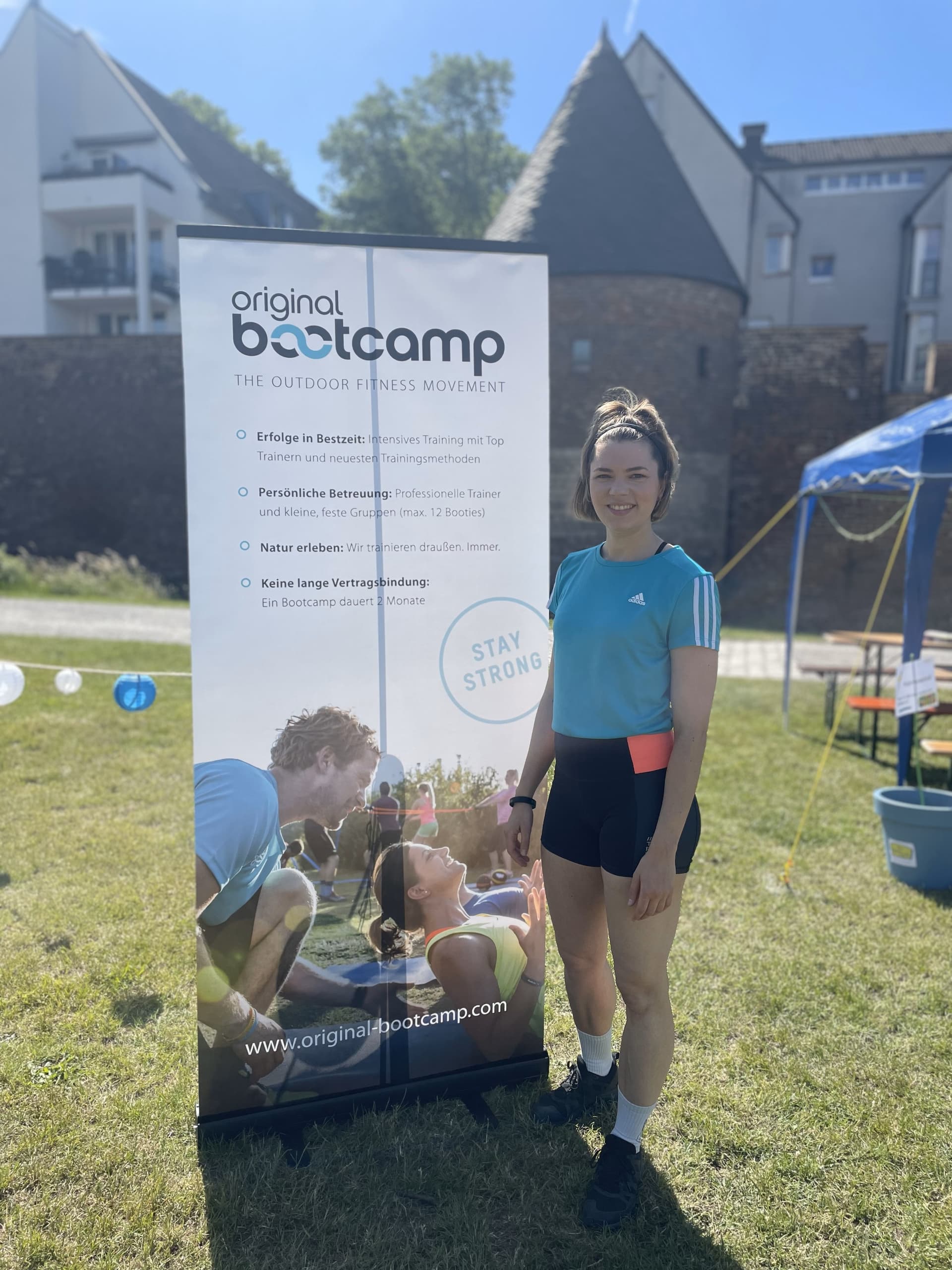 Personal Training Evelyn Stoll Duisburg steht vor einem Original Bootcamp Aufsteller