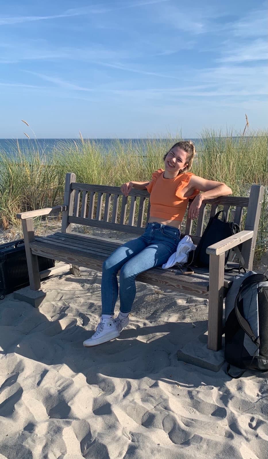 Evelyn Stoll aus Köln sitzt in der Sonne auf einer Bank am Meer