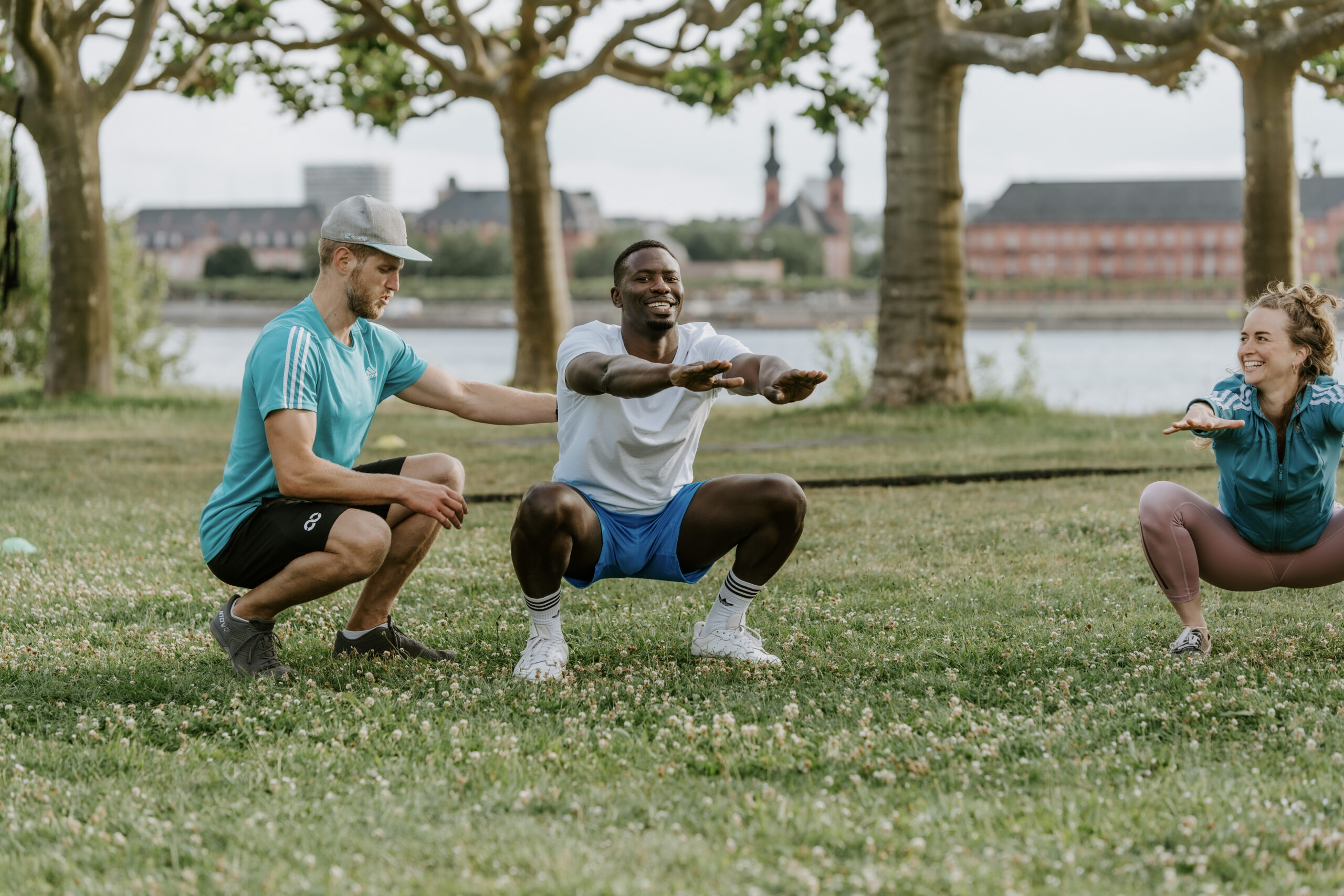 Personal Trainer Kosten: Trainer coacht Person beim Outdoor-Squats-Training