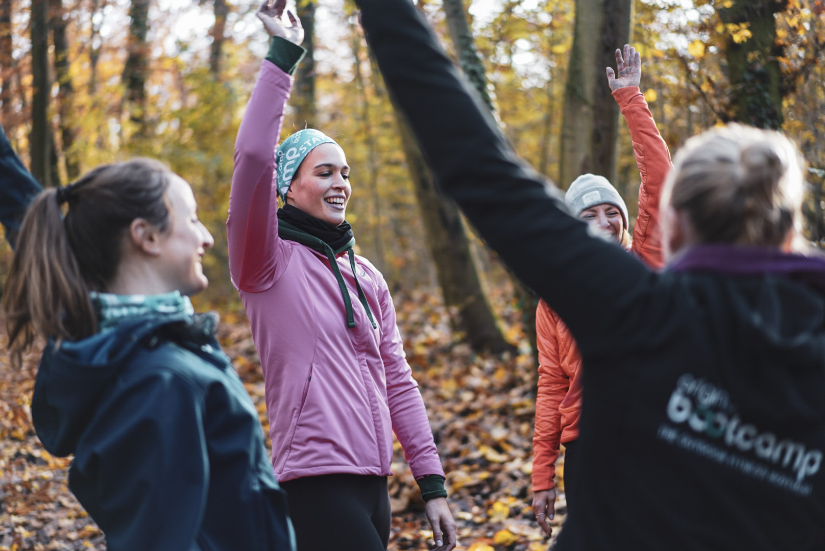 Pace-Training im Herbst: Laufgruppe feiert Erfolg mit erhobenen Armen im Wald