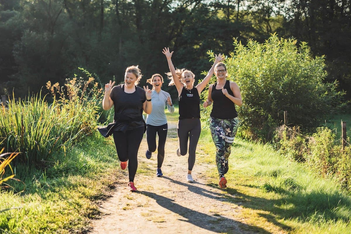Vier glückliche Frauen klatschen nach einem intensiven Outdoortraining ab