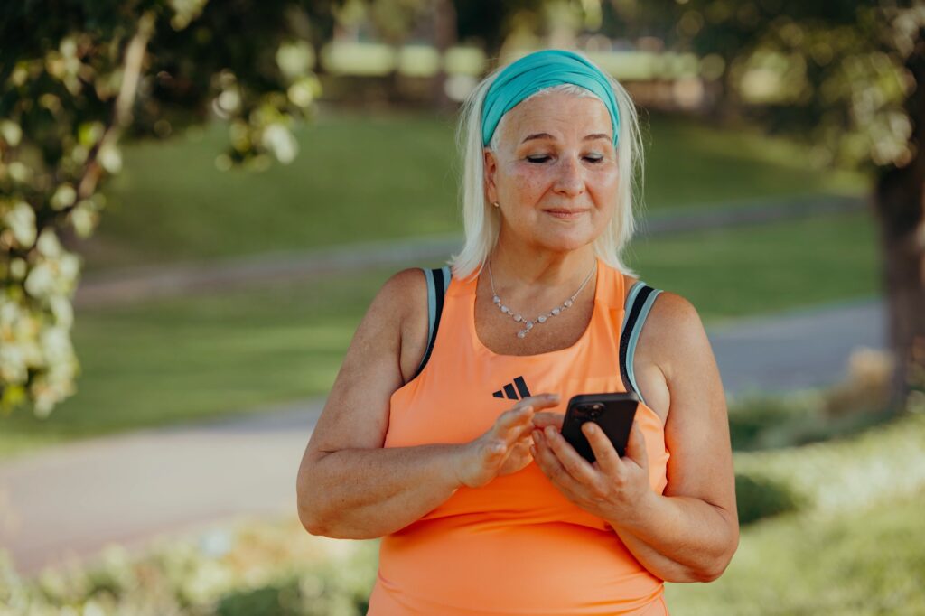 Geschenk für Sportler: Trainingsfortschritt tracken Geschenk für Sportler: Teilnehmerin schaut nach dem Outdoor-Training auf ihr Smartphone