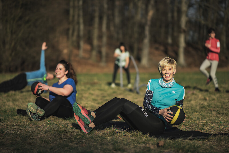 Zirkeltraining Übungen mit Medizinball im Park mit motivierter Trainingsgruppe