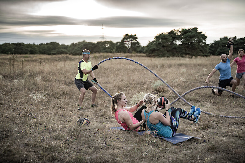 Teilnehmer:innen trainieren gemeinsam im Freien mit Battle Ropes und Medizinbällen – intensives Zirkeltraining für Muskelaufbau und Kraftausdauer.