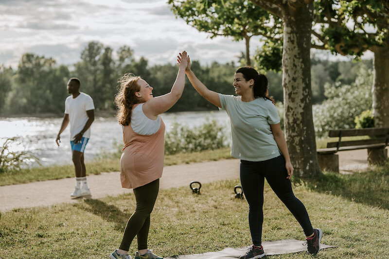 Zwei Frauen geben sich ein High-Five nach dem Training – gemeinsames Zirkeltraining zuhause mit Spaß und Zusammenhalt.