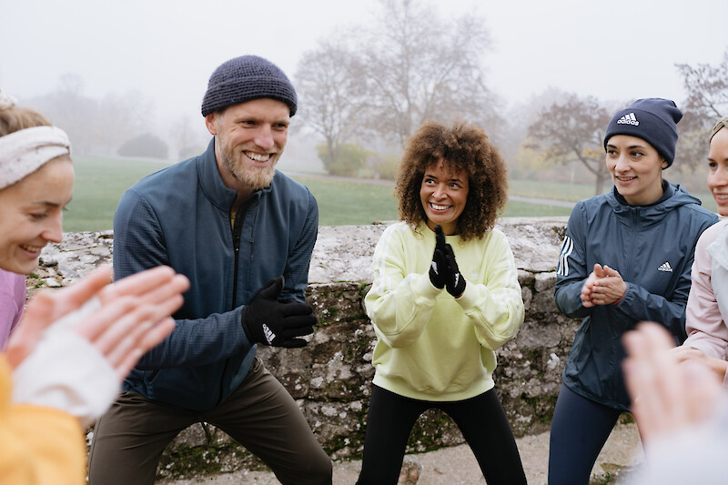 Outdoor-Fitness Warm-up im Park bei kühlem Wetter in motivierender Gruppenatmosphäre.
