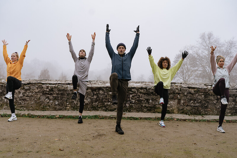 Outdoor-Fitness Workout mit einer Trainingsgruppe, die koordinierte Kniehebeläufe im Park ausführt.