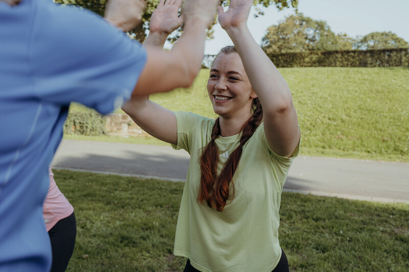 Neujahr Fitness: Motivierende High-Five-Szene im Gruppentraining, Gemeinschaft und Spa&szlig; als Schl&uuml;ssel f&uuml;r langfristige Fitnessvors&auml;tze.